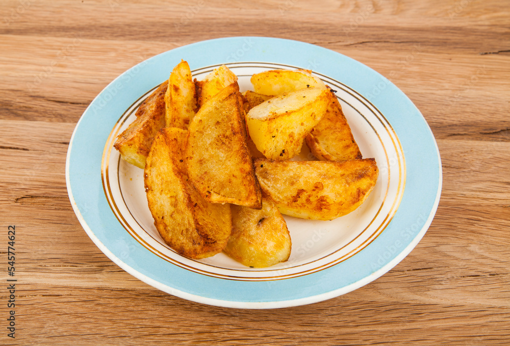 Fried potatoes in a plate on a wooden background. Fried potatoes in a plate on a wooden background.