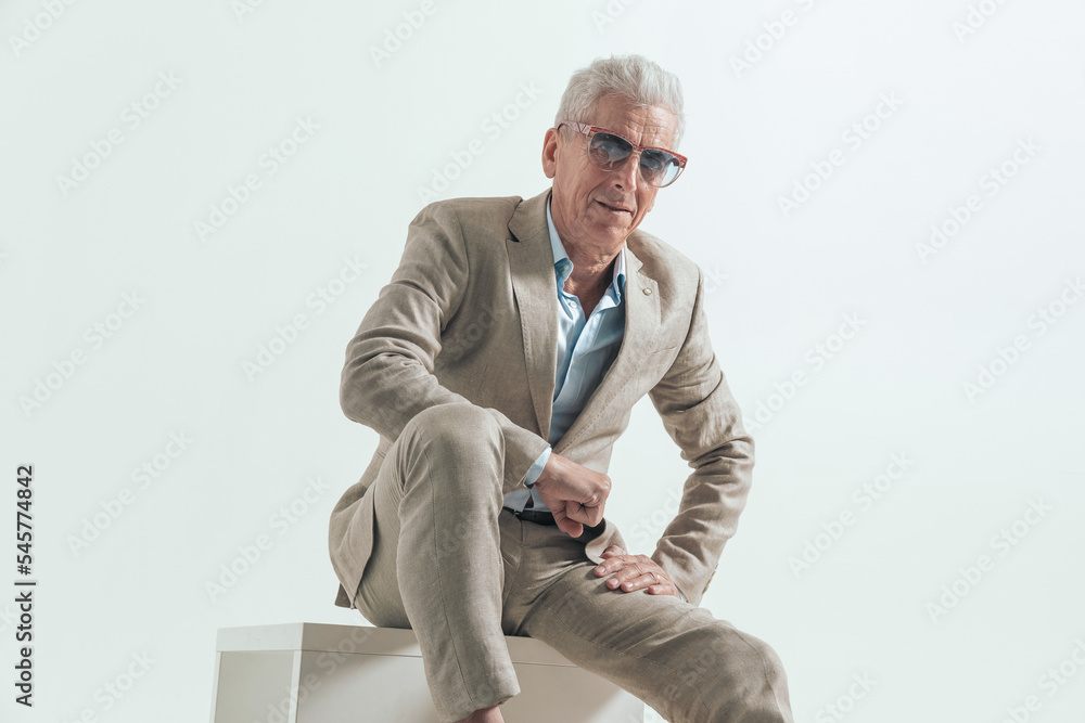 happy elegant guy in suit holding arm on knee, smiling and sitting happy elegant guy in suit holding arm on knee, smiling and sitting
