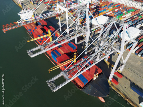 Aerial view of Industrial shipping port. View from drone. Loading containers on the ship, cranes load containers.