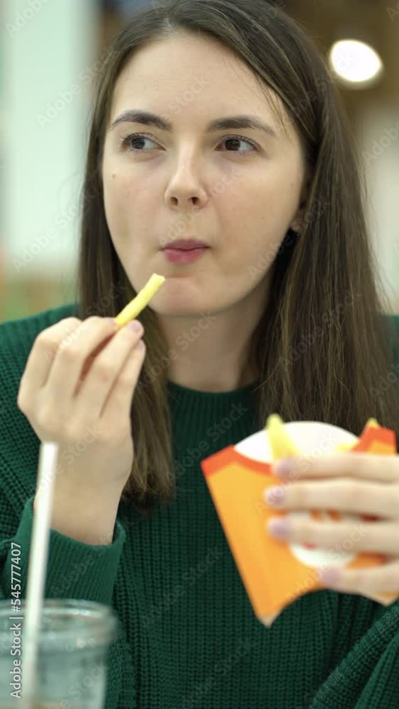 woman eating french fries and cola at the food court. woman eating french fries and cola at the food court.