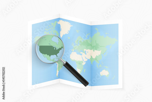 Enlarge USA with a magnifying glass on a folded map of the world.