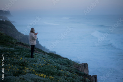 Woman stands on the Atlantic coast in the early morning.