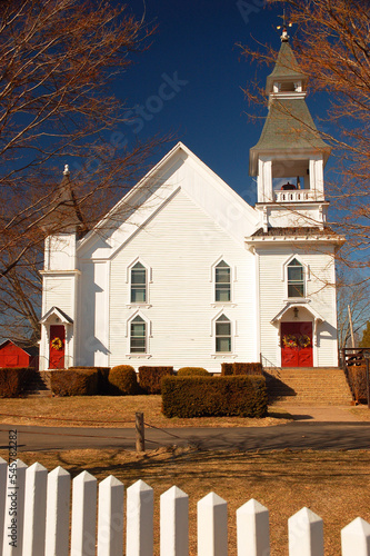 The white Hebron First Congregational Church in New England is surrounded by a white picket fence photo