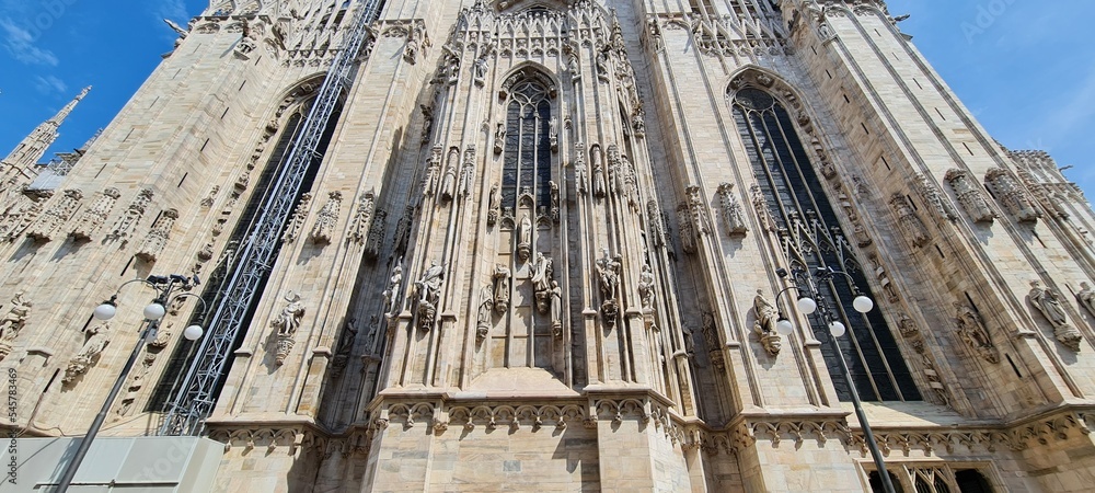 Cathedral Duomo di Milano. Panoramic view of the ornate facade with many marble sculptures on the wall. Entrance to the cathedral of European country. Detail of a building.