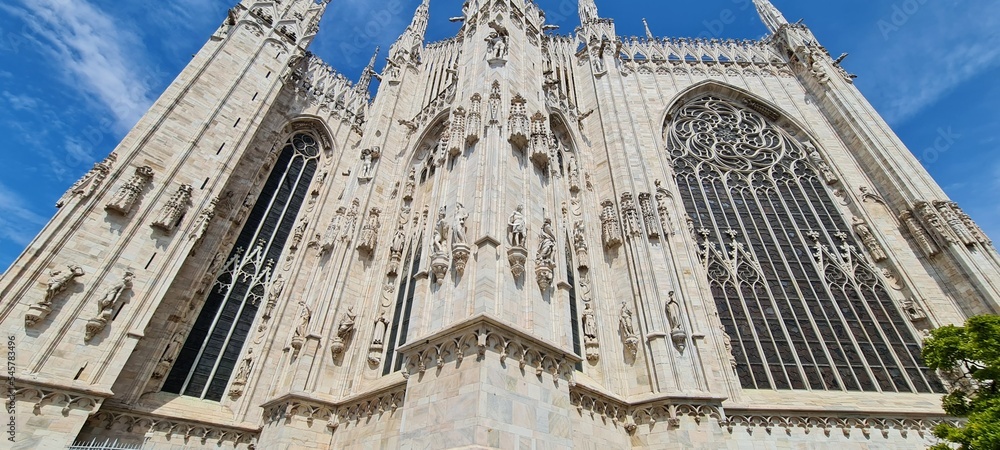 Naklejka premium Cathedral Duomo di Milano. Panoramic view of the ornate facade with many marble sculptures on the wall. Back view of the cathedral of European country. Detail of a building.