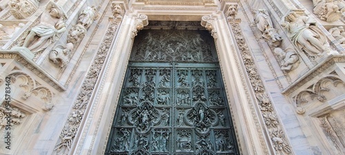 Cathedral Duomo di Milano. Panoramic view of the ornate facade with many marble sculptures on the wall. Entrance to the cathedral of European country. Detail of a building.