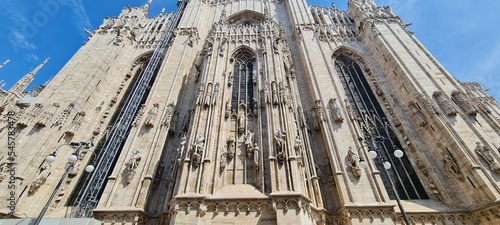 Cathedral Duomo di Milano. Panoramic view of the ornate facade with many marble sculptures on the wall. Entrance to the cathedral of European country. Detail of a building.