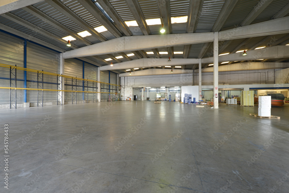 Empty interior of an industrial warehouse with polished concrete floors and concrete ribs supporting the ceiling