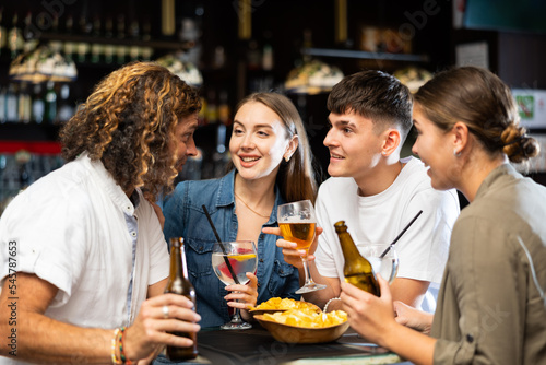 Group of happy friends enjoying beer  crisps and talks in the evening pub