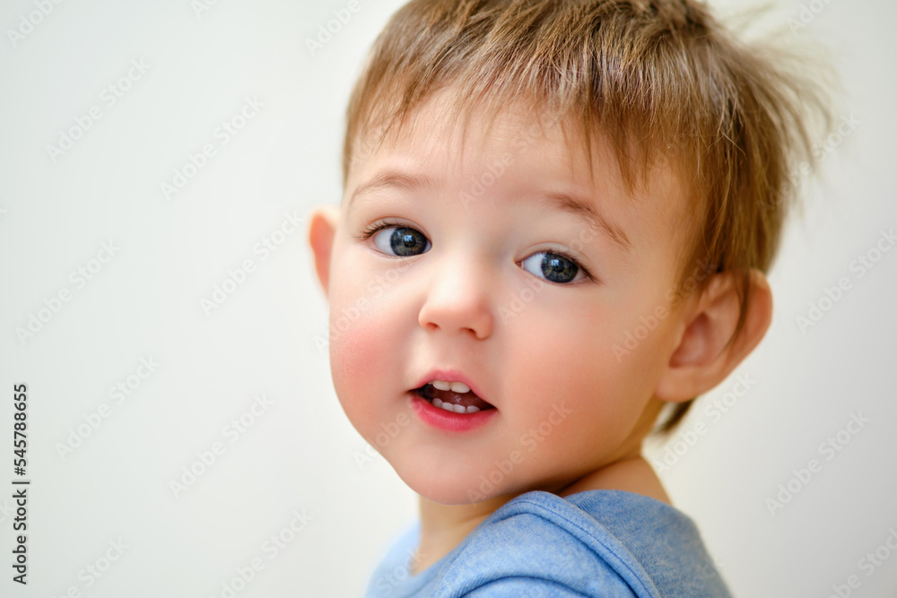 Portrait of a toddler baby boy on the background of a home room. The face of a child with disheveled hair in the nursery Portrait of a toddler baby boy on the background of a home room. The face of a child with disheveled hair in the nursery