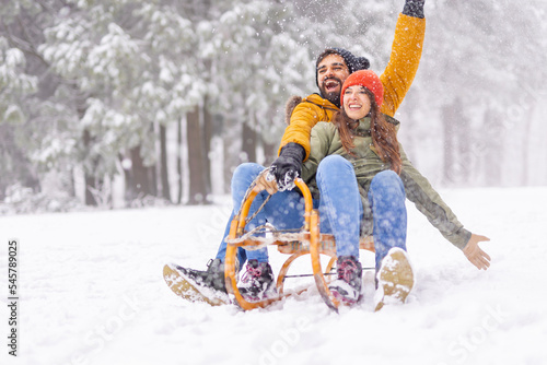 Couple having fun sledging while on winter vacation photo