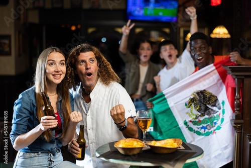 Joyful fans of the Mexican team celebrating the victory in the night bar