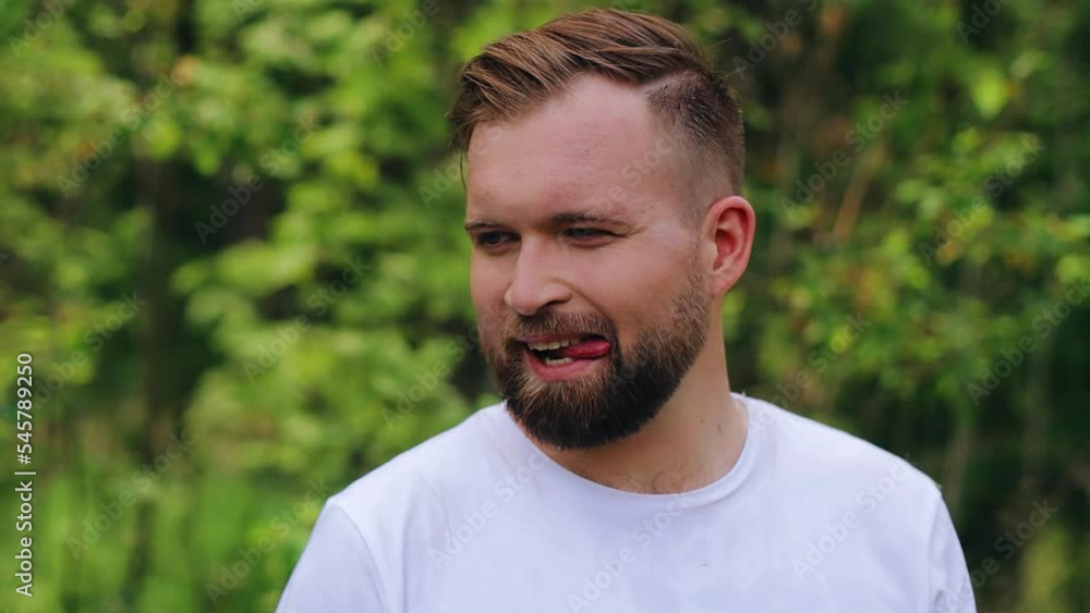 The bearded guy shows his tongue and smiles looking away. The camera takes a close-up of him The bearded guy shows his tongue and smiles looking away. The camera takes a close-up of him