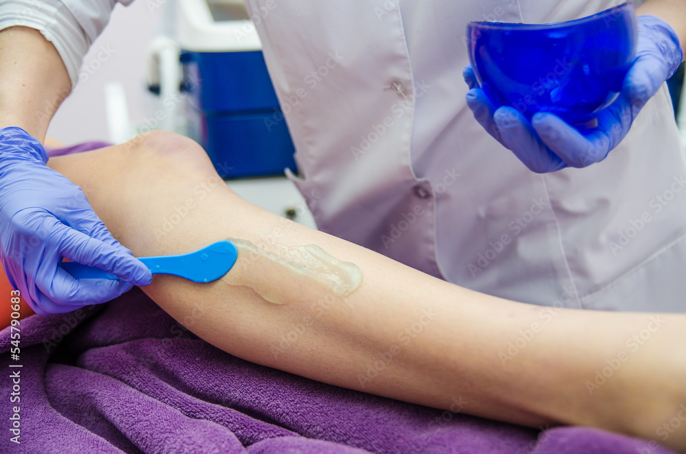 Doctor cosmetologist makes a laser dermal rejuvenation procedure to a patient. Against the background of a medical office