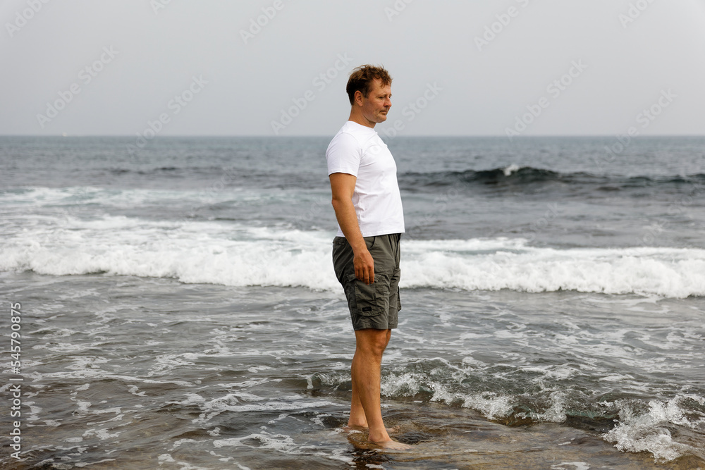 A young handsome man walks by the sea, the concept of a healthy lifestyle