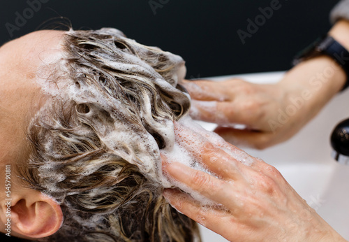 Woman with hairdresser washing head at hair salon