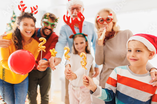 Family celebrating New Year holding balloons shaped as numbers 2023