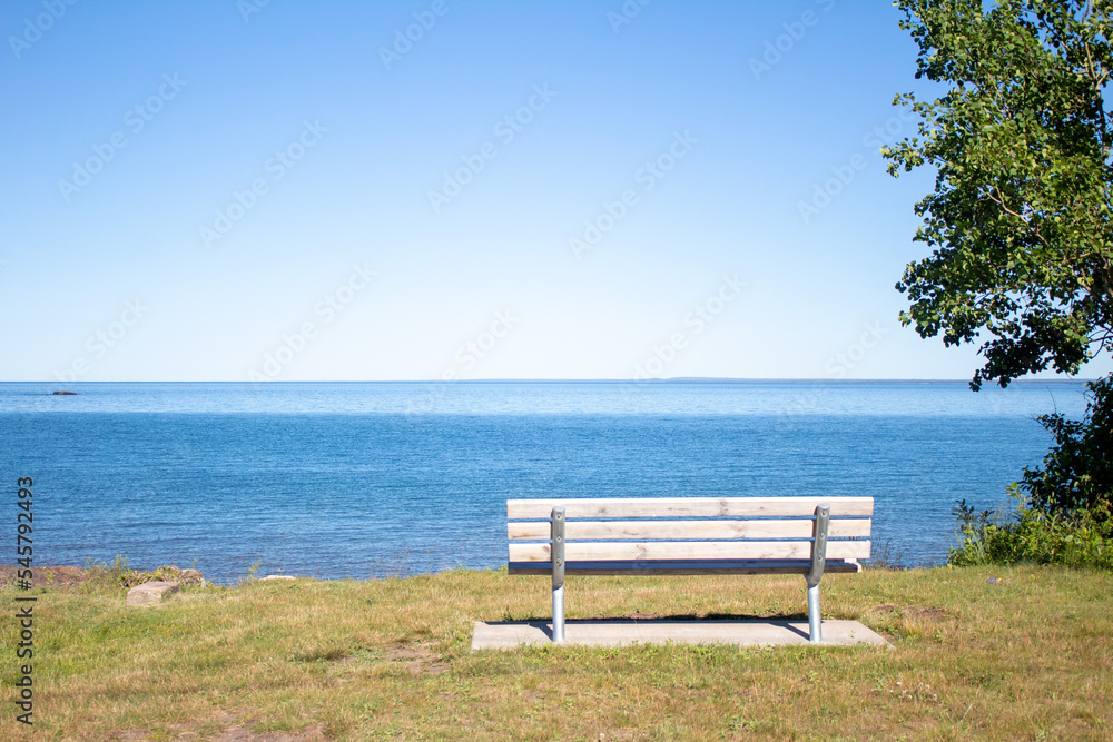 Empty bench in field of grass looking over a body of water