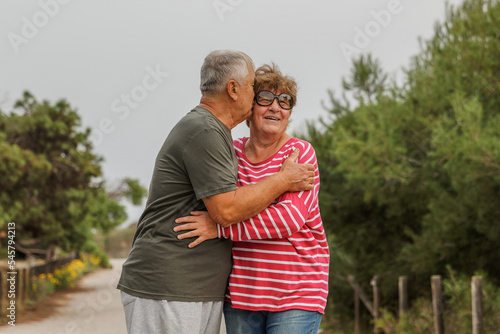 Happy elderly couple embracing in park on sunny day, love together in Valentines day concept, senior couple anniversary