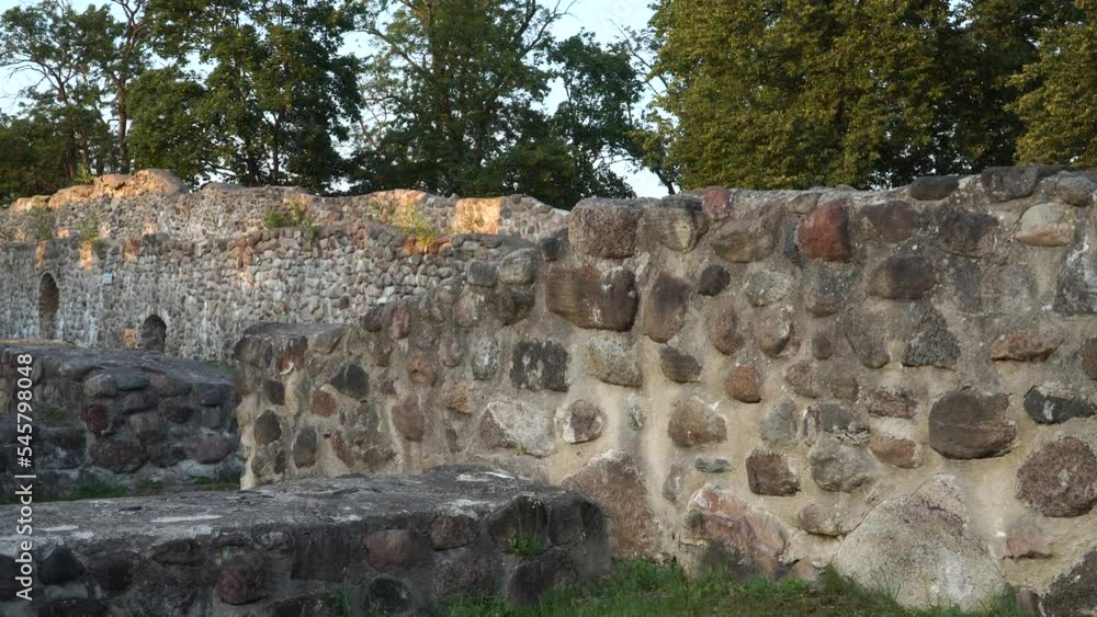 Stone walls and fundamentals of the Dobele castle ruins in Latvia, scenic view in summer. The rough texture of ancient wall fragments nearby in a close-up. Stone walls and fundamentals of the Dobele castle ruins in Latvia, scenic view in summer. The rough texture of ancient wall fragments nearby in a close-up.
