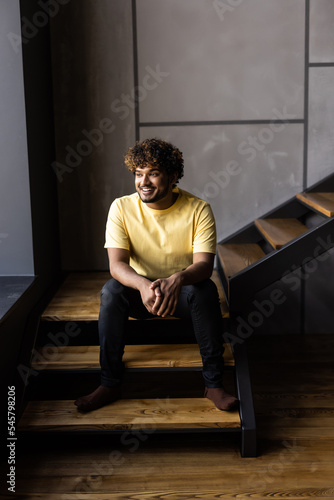 Low angle indian man sitting on steps at home