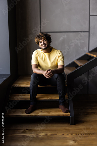 Low angle indian man sitting on steps at home