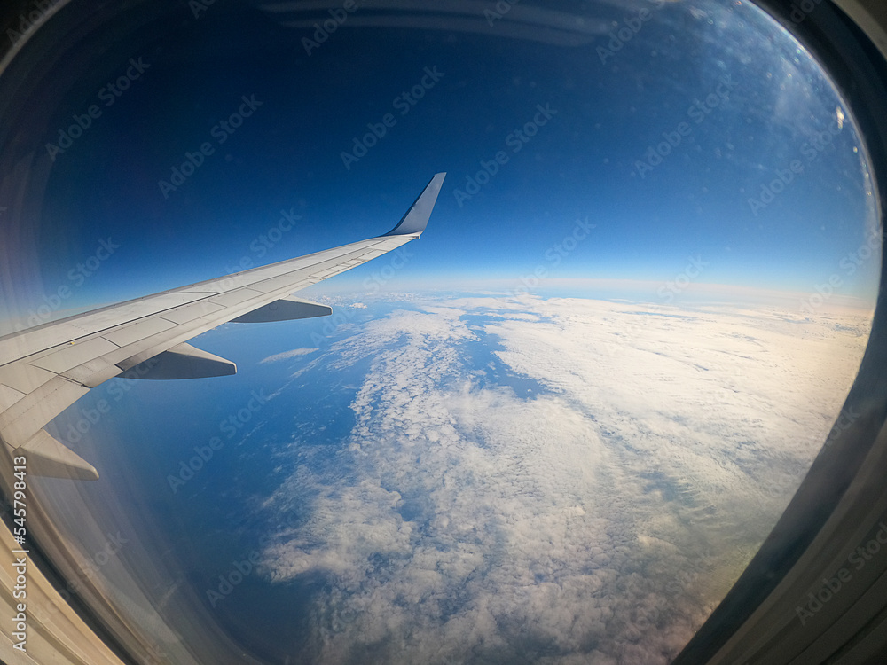 view of the clouds and the wing of an airplane from the window on a sunny day view of the clouds and the wing of an airplane from the window on a sunny day