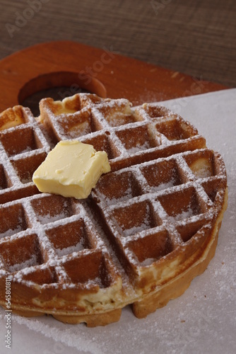 singlel waffle with butter, powdered sugar and unpoured syrup