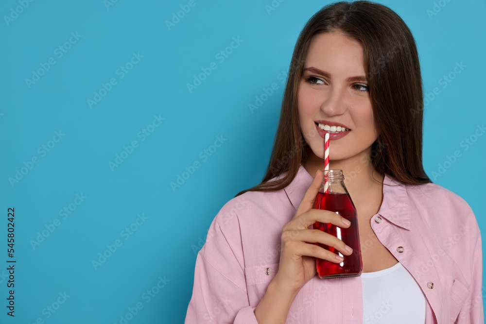 Beautiful young woman with glass bottle of juice on light blue background. Space for text Beautiful young woman with glass bottle of juice on light blue background. Space for text