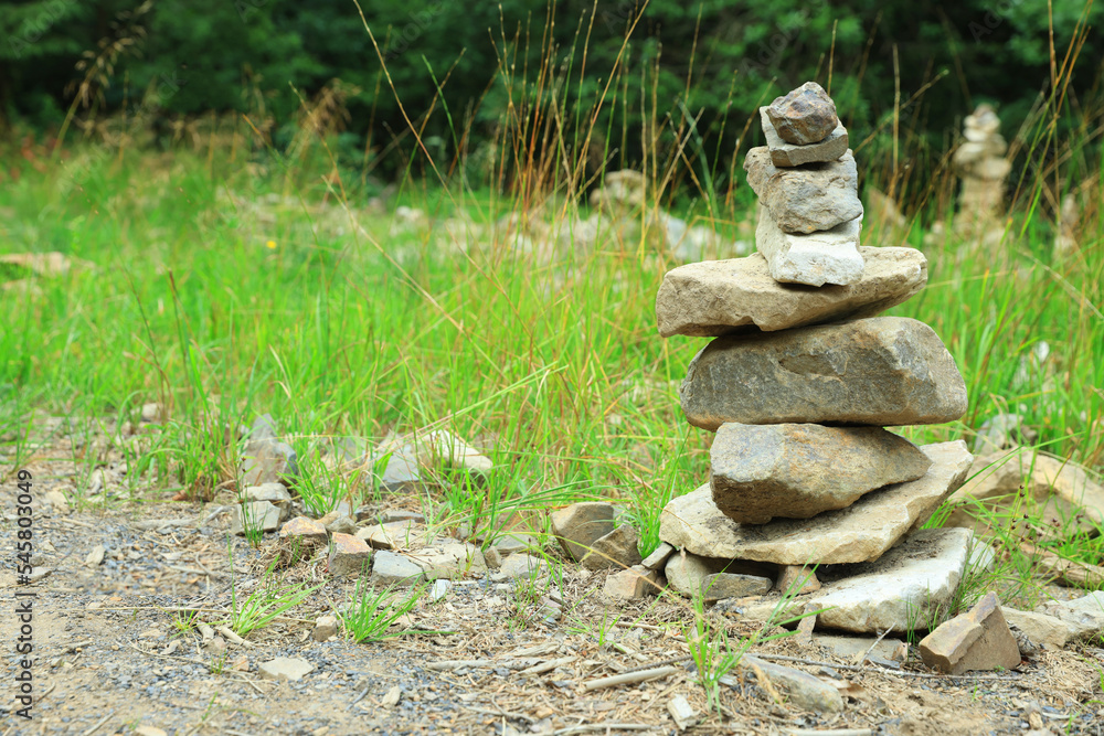 Many stacked stones on green grass outdoors, space for text Many stacked stones on green grass outdoors, space for text