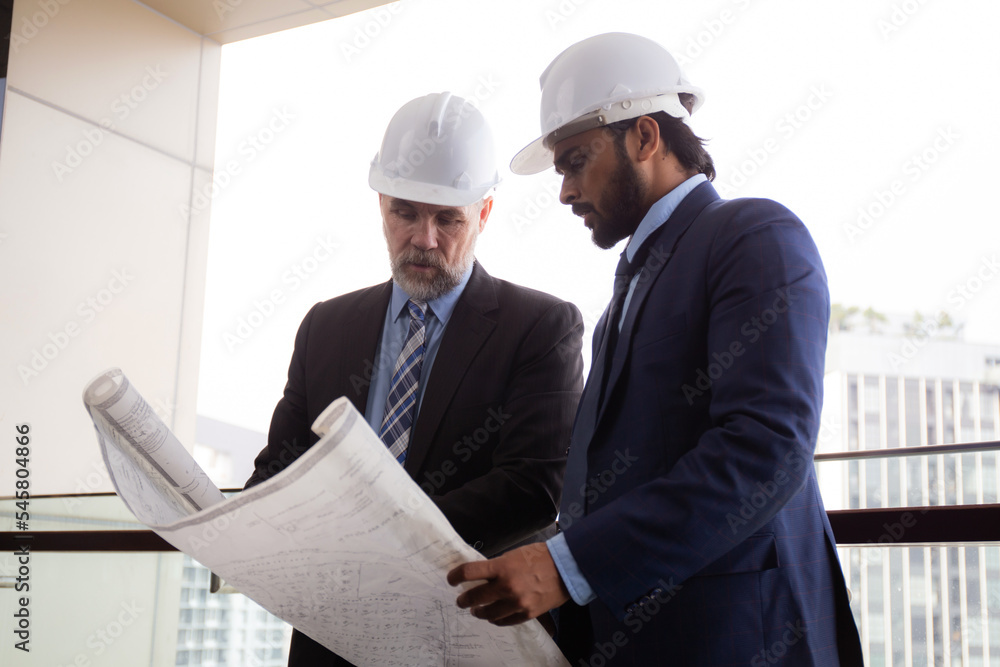 Senior architect inspector check blueprint and structure with contractor man and talking together at office, executive and supervisor or engineer planning project, industry and construction concept. Senior architect inspector check blueprint and structure with contractor man and talking together at office, executive and supervisor or engineer planning project, industry and construction concept.
