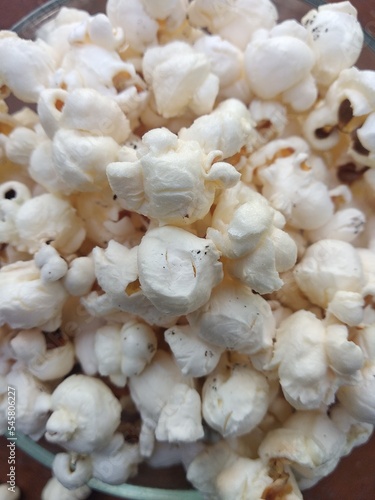 Pop corn on a wooden bottomed glass container. white popcorn.