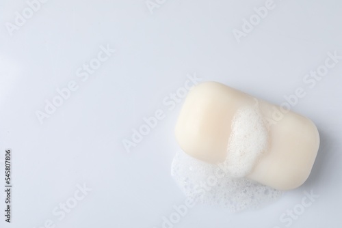 Soap with fluffy foam on white background, top view. Space for text