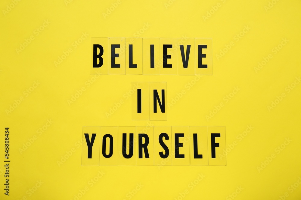 Phrase Believe In Yourself and hearts on yellow background, top view. Motivational quote Phrase Believe In Yourself and hearts on yellow background, top view. Motivational quote