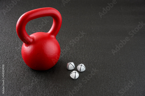 Holiday fitness, red kettlebell on a gym floor with jingle bells for Christmas spirit
