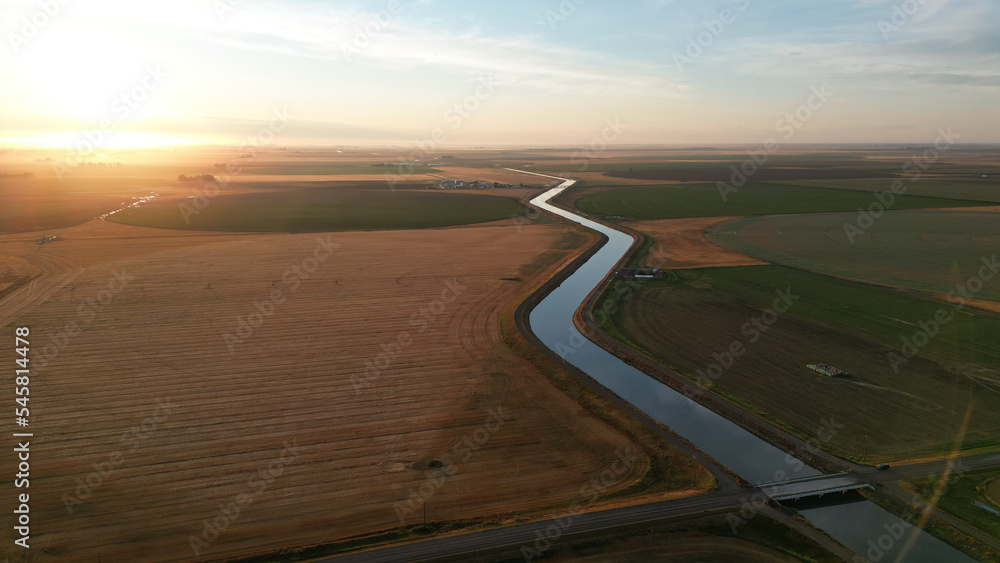 Drone view during sunrise over a farm hay field and river in Alberta Canada