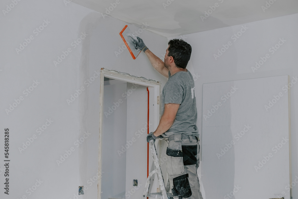 A young builder is plastering a doorway. A young builder is plastering a doorway.