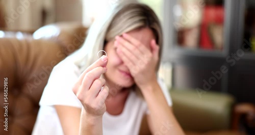 Unhappy woman holding wedding ring closeup