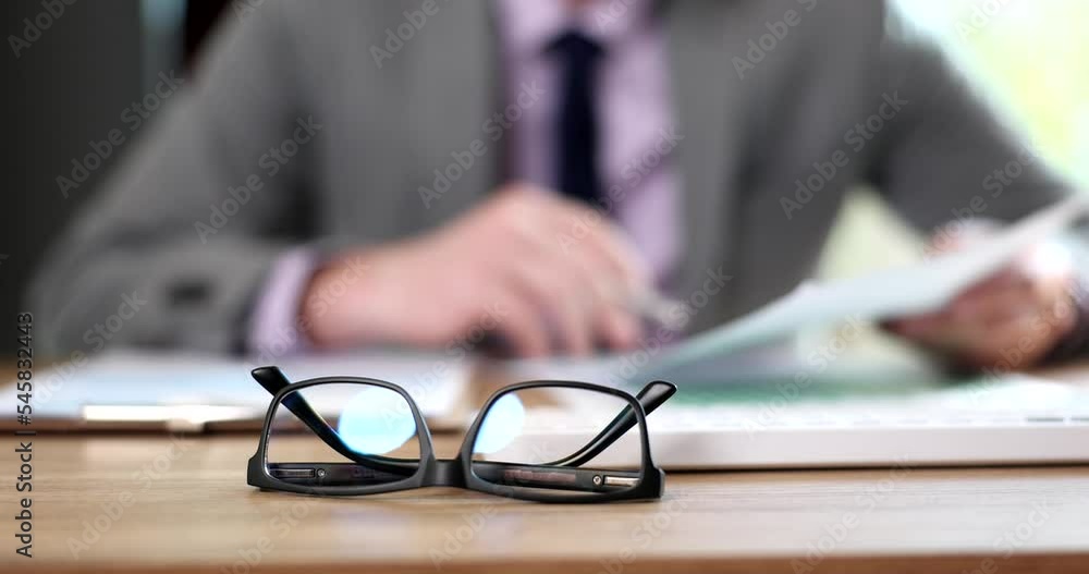 Glasses on the background of businessman studies financial documents Glasses on the background of businessman studies financial documents