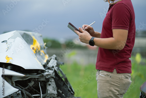 Car insurance agent is checking assess the damage and writing on tablet while examining car after accident, Car insurance concept. photo