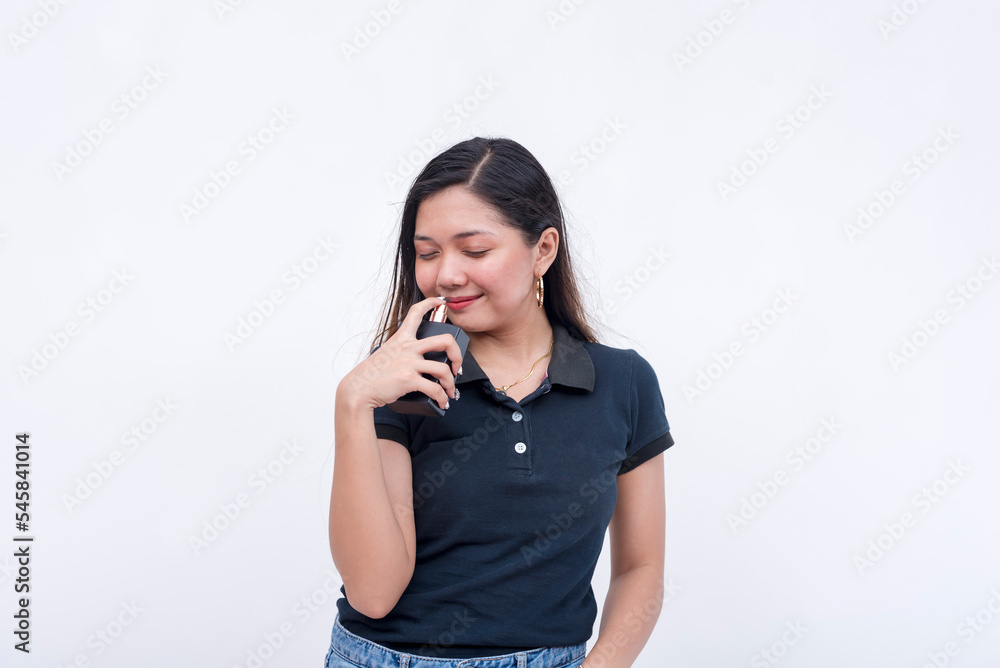 A young asian woman smelling light cologne. Isolated on a white background. A young asian woman smelling light cologne. Isolated on a white background.