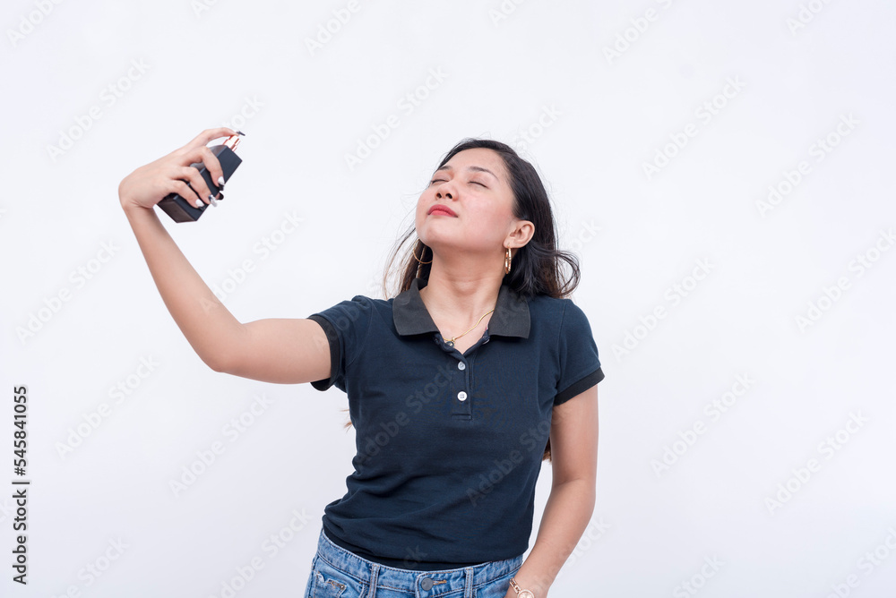 A young asian woman sprays light cologne on her neck. Isolated on a white background. A young asian woman sprays light cologne on her neck. Isolated on a white background.