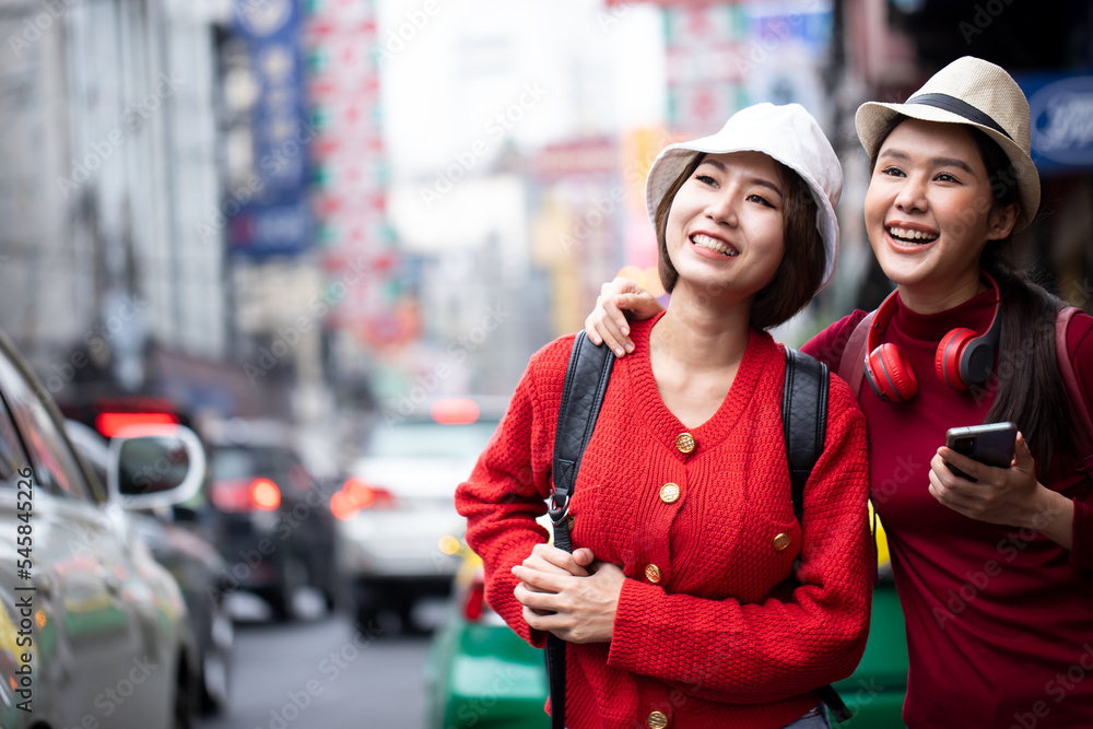 Asian women walking and using a smartphone in the street in a sunny summer day. Summer sunny lifestyle fashion portrait of young stylish hipster woman walking on the street. Friendships and travel. Asian women walking and using a smartphone in the street in a sunny summer day. Summer sunny lifestyle fashion portrait of young stylish hipster woman walking on the street. Friendships and travel.