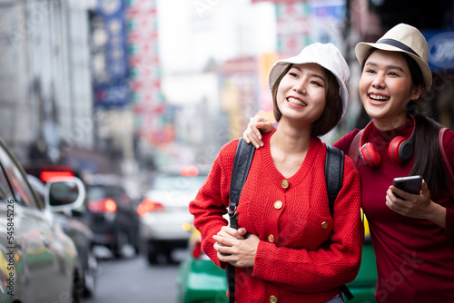 Asian women walking and using a smartphone in the street in a sunny summer day. Summer sunny lifestyle fashion portrait of young stylish hipster woman walking on the street. Friendships and travel. © krumanop