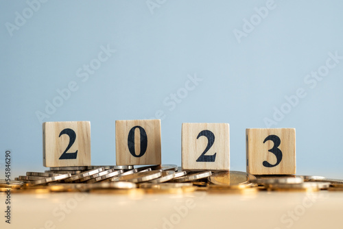 2023 Happy New Year. Business and saving money, Financial growth, interest rate increase, inflation, sale price and tax rise concept. wooden blocks number 2023 on coins.