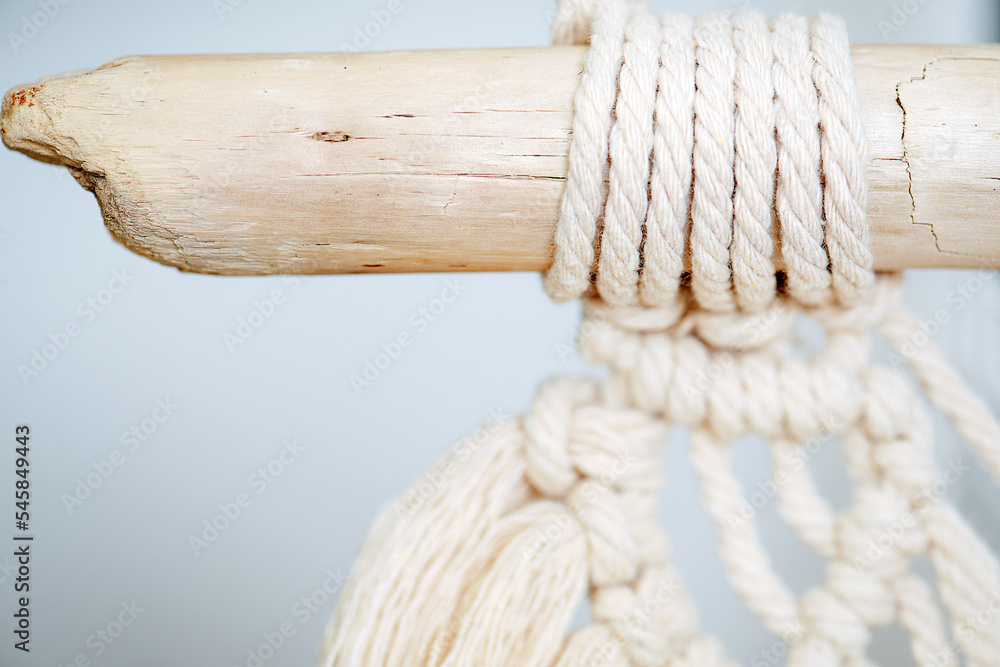 Close up shot of macrame piece tied to a cracked river washed stick. Focus on the loop part. Close up shot of macrame piece tied to a cracked river washed stick. Focus on the loop part.