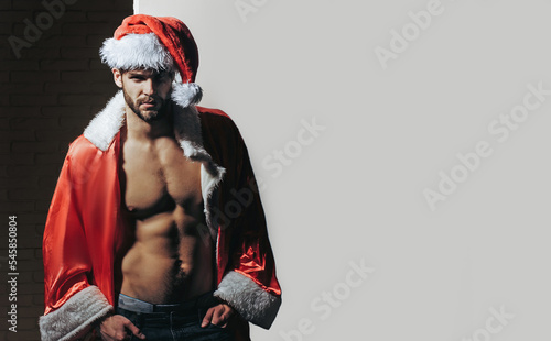 Christmas sexy gay. Young men in santa hat. Santa with muscular body. Handsome sexy santa claus guy on studio background. Sexy Santa Claus.