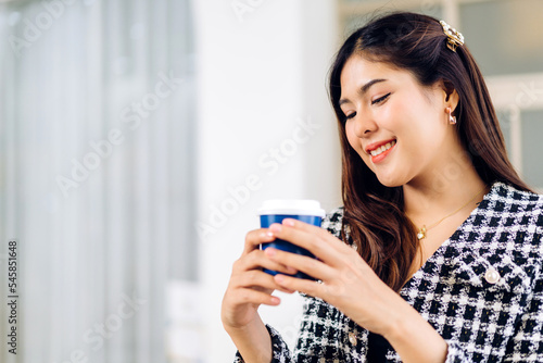 Portrait of smiling happy cheerful beauty pretty asian woman relaxing drinking and looking at cup of hot coffee or tea.Girl felling enjoy having breakfast at cafe