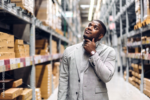 Portrait of smiling african american business man order details checking goods and supplies on shelves with goods background in warehouse.logistic and business export