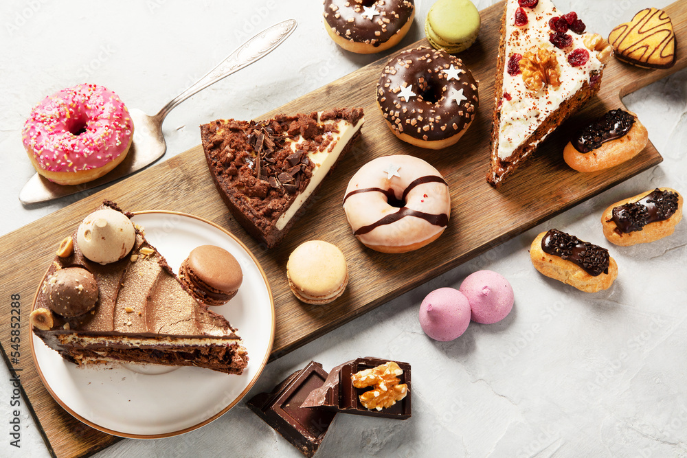 Table with various cakes, cookies, donuts and coffee cups on light background. Table with various cakes, cookies, donuts and coffee cups on light background.